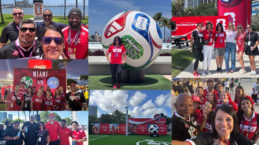SimoneF2-FIFA Experience - Coca-Cola Beverages Florida Group of Coca-Cola staff and fans in red shirts posing for photos at FIFA World Cup Miami events, with water and palm trees in the background and a large branded soccer sculpture nearby.