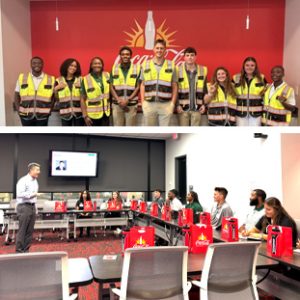 Diverse group of people in high-visibility vests posing in front of a red wall with a sunburst logo for safety/crew photo.
